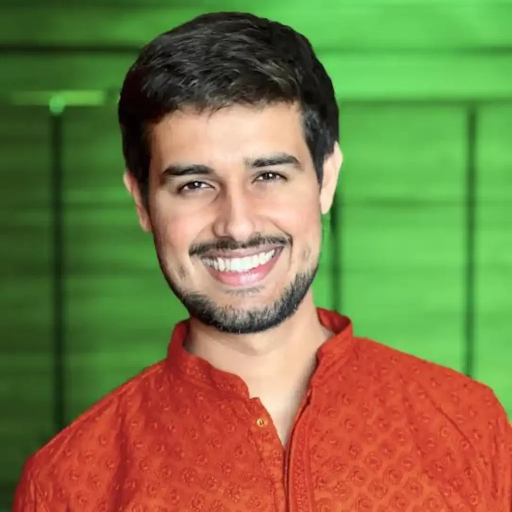 Dhruv Rathee smiling in traditional orange kurta against green background.