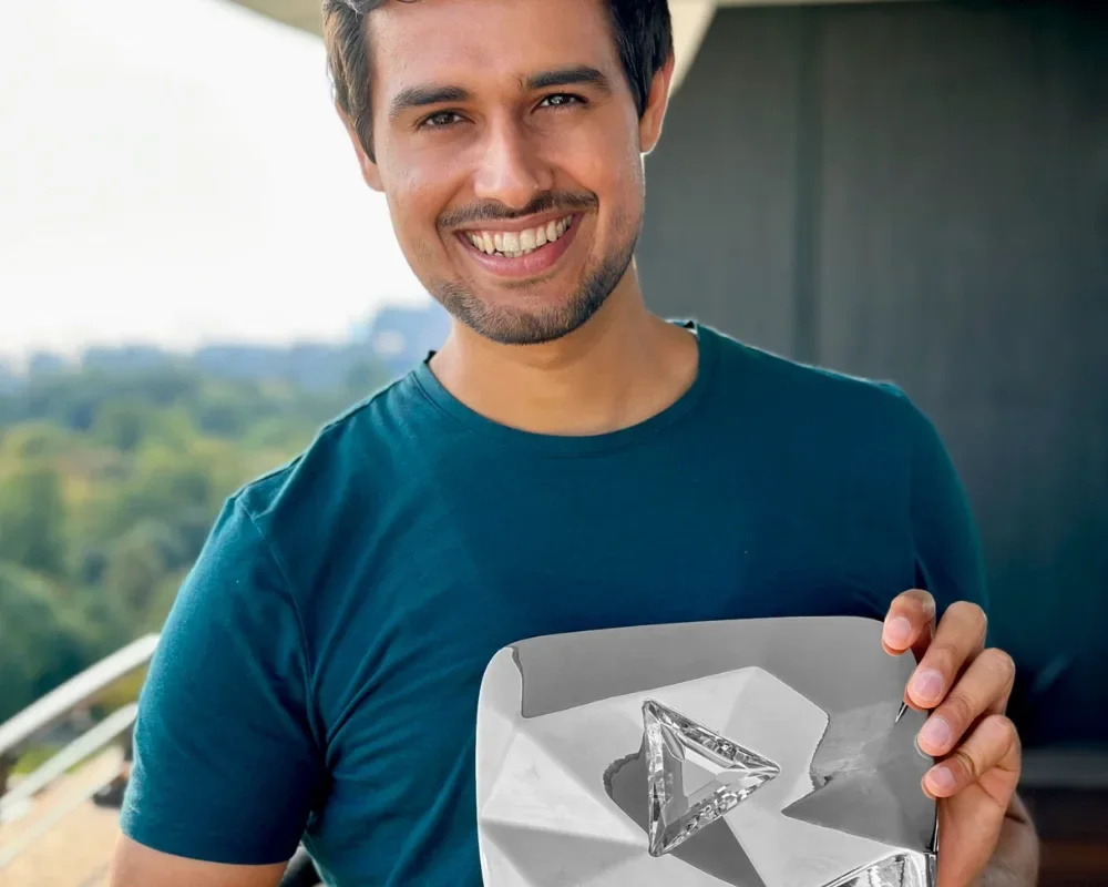 Dhruv Rathee smiling while holding a YouTube play button award.