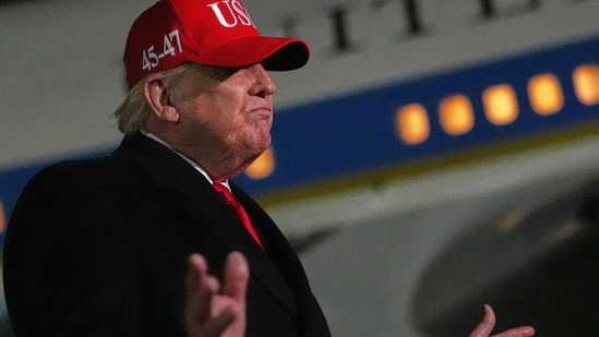 Donald Trump in a red cap speaking at an event, with his face blurred in the image.