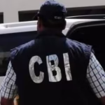 CBI officer standing near a vehicle during an ongoing investigation.