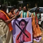Women protesters holding a poster of Dhirendra Shastri with a black cross mark during a protest in Nagpur.