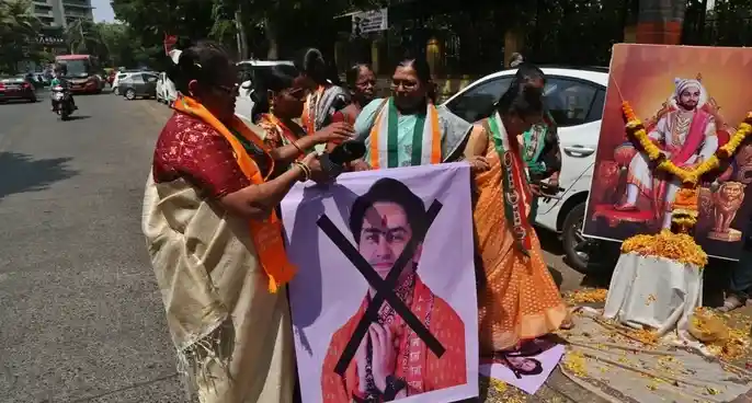 Women protesters holding a poster of Dhirendra Shastri with a black cross mark during a protest in Nagpur.